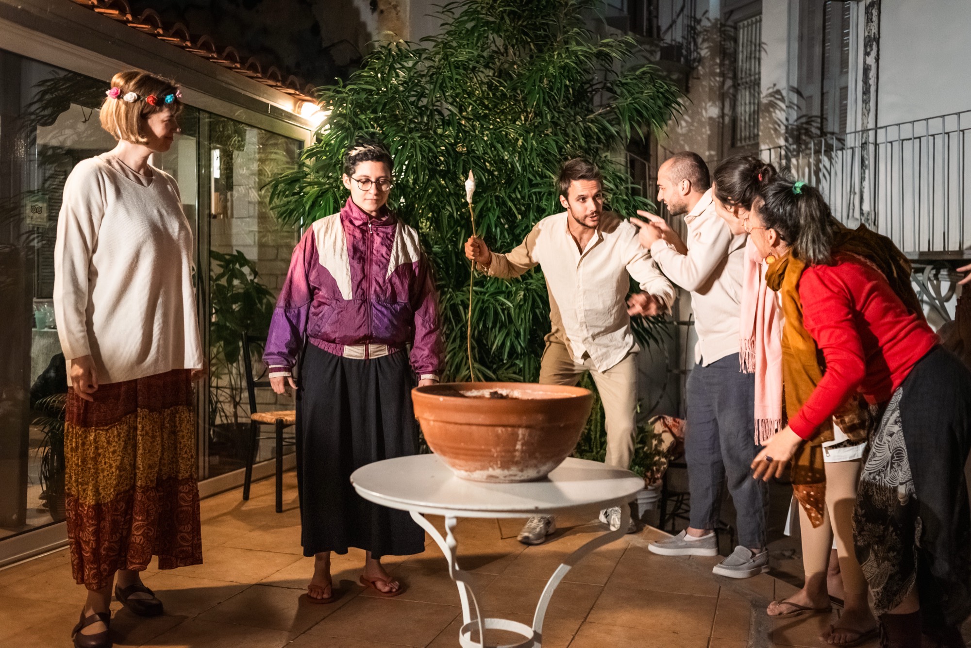 Elenco reunido no pátio durante a temporada na Grécia, sob luz de fim de tarde.
