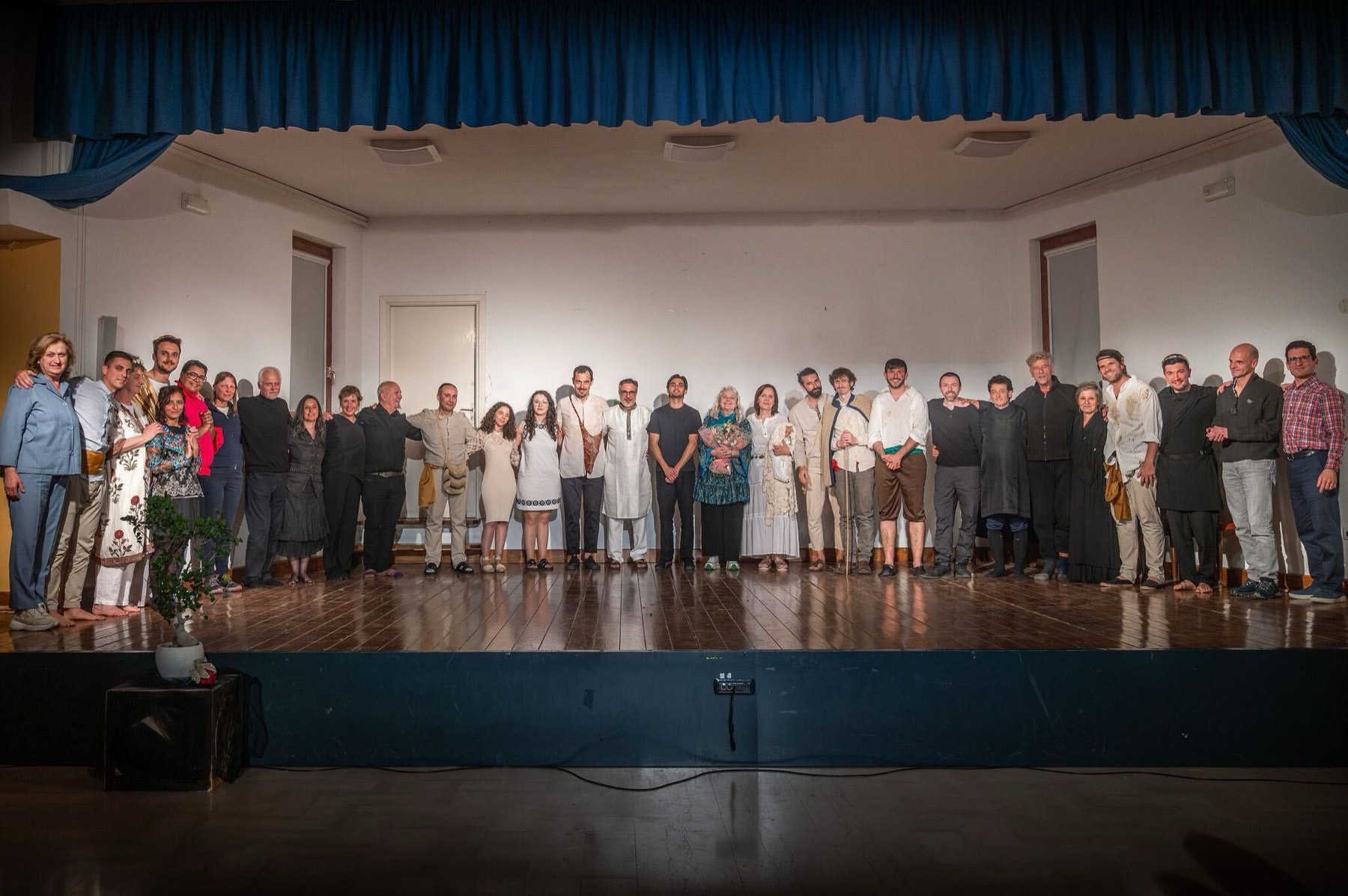 Elenco completo em fila no palco ao final da apresentação.
